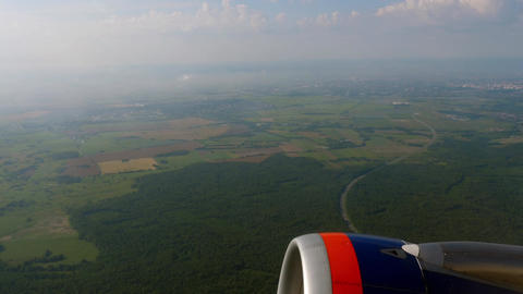 Airplane engine flying over green fields aerial view
