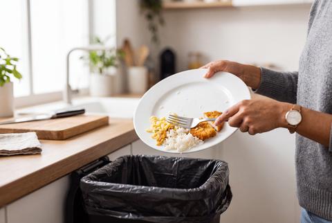 Person Scraping Leftover Food Waste into Kitchen Garbage Bin