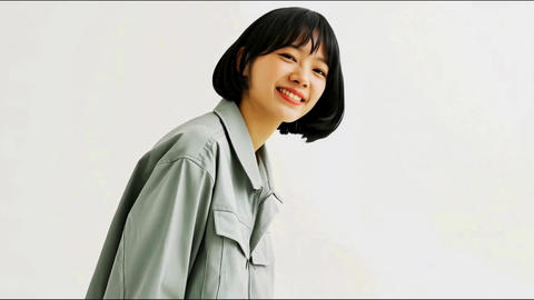 Profile view of a smiling young Japanese woman in workwear (white background, copy space)