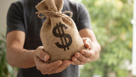 Man Holding Burlap Money Bag with Dollar Sign for Financial Wealth and Savings