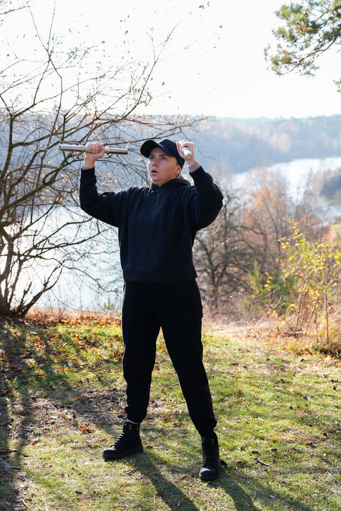 Young woman wearing black hoodie and cap performs strength exercise with
