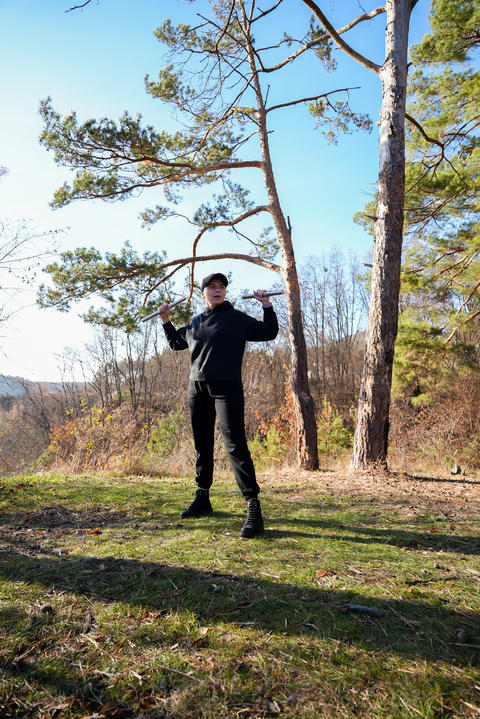 Young woman wearing black hoodie and cap performs strength exercise with