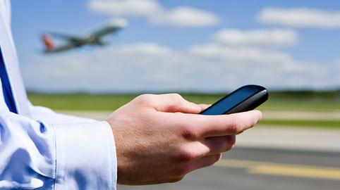 Business traveler holding smartphone with airplane taking off