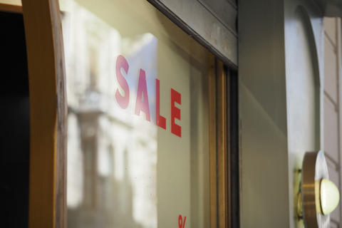 Window display shows sale sign in a store in a busy shopping area