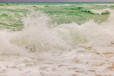 Close-up view of Atlantic Ocean waves crashing onto sandy shore with splashing water and sea foam