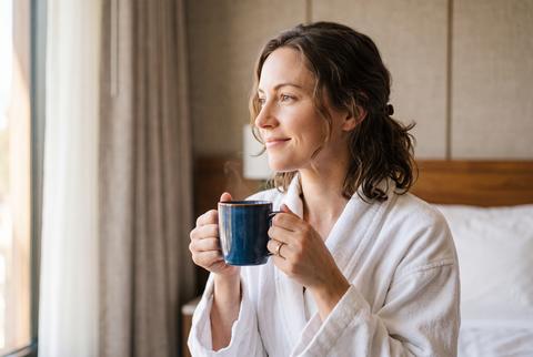 Woman in White Bathrobe Holding Coffee Mug in Hotel Room Morning