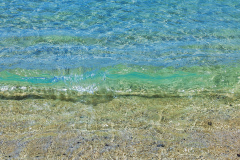 Close-up view of clear Atlantic Ocean waves washing over sand at Amadores beach, Gran Canaria