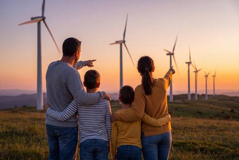 Family Looking at Wind Turbines on Hill at Sunset