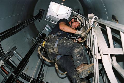 Wind Turbine Technician Climbing Ladder Wearing Safety Harness