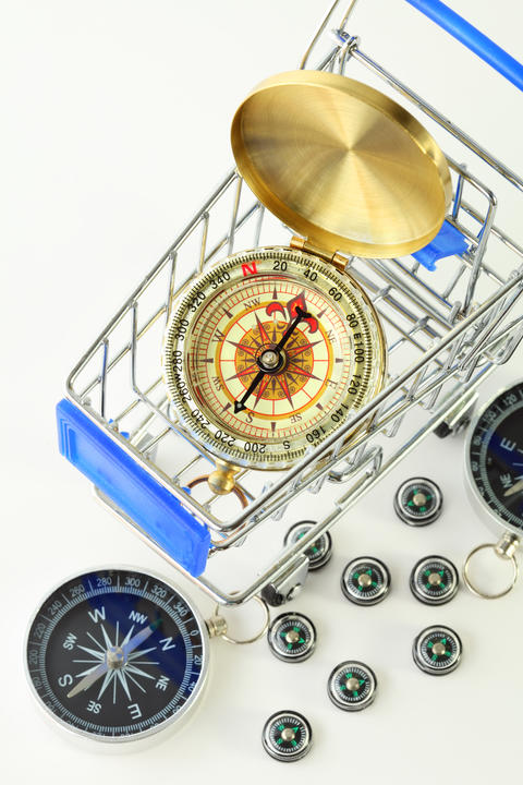 Metal compasses rest in shopping cart with round brass lid