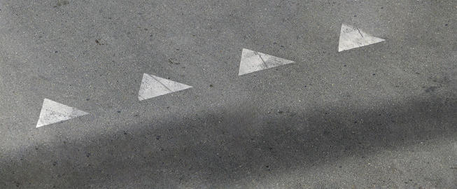 White triangle road markings on gray asphalt