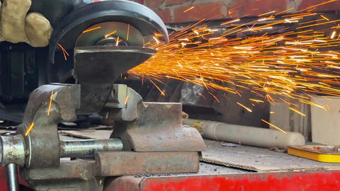 Male hands in gloves sharpening an axe blade with angle grinder in garage