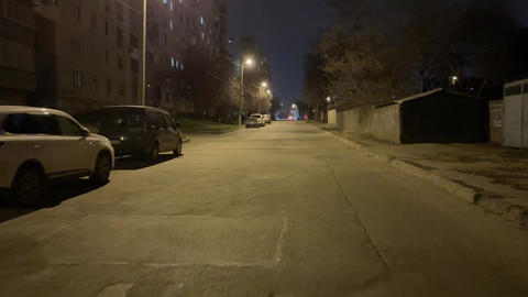 Rear view of young man run away along suburban street at evening time