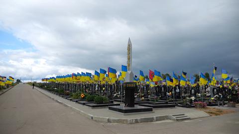 View on countless graves of ukrainian soldiers alley of glory in Kharkiv decorated with waving blue-