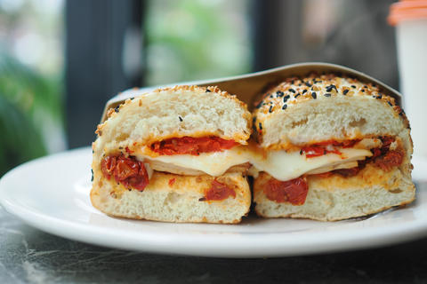 Sesame seed bagel sandwich with melted cheese and roasted tomatoes cut in half