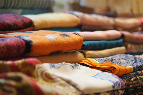 Colorful folded patterned fabrics stacked on market table for sale