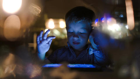 Boy playing on tablet computer in cafe