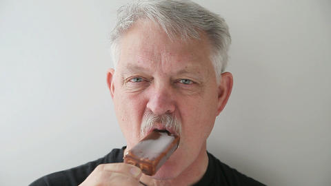 senior man eats ice cream bar
