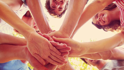 Happy friends stacking hands together in the park