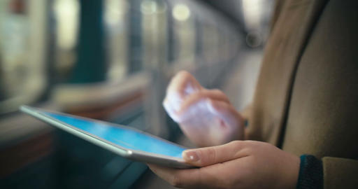Woman using tablet PC by the leaving train in subway