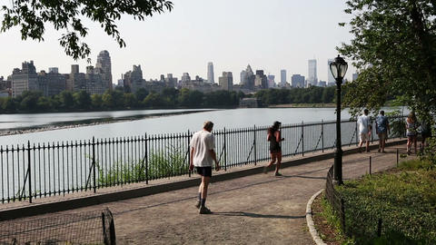 Strolling in the park a sunny day. Joggers and tourists