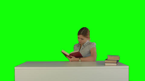 Female student reading a book for finding information on a Green Screen