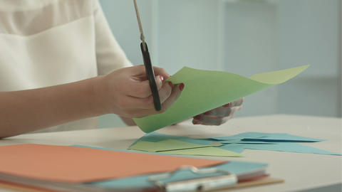 Woman is cutting green paper using scissors